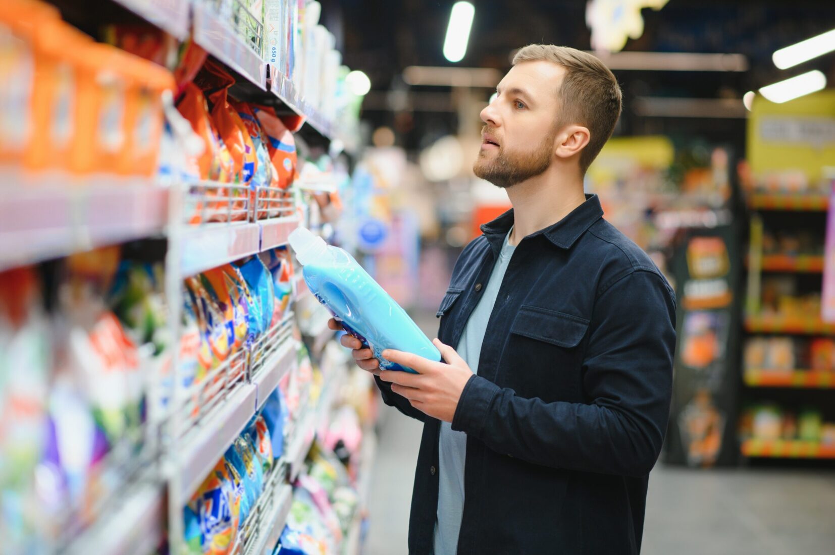 Young man in the supermarket in the household chemicals department.